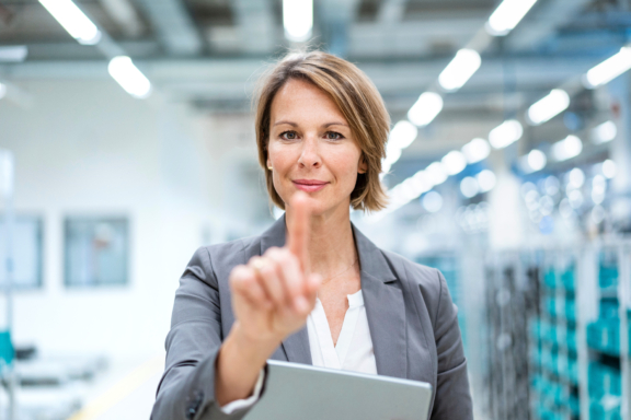 Portrait of businesswoman with tablet in a modern factory touching virtual screen